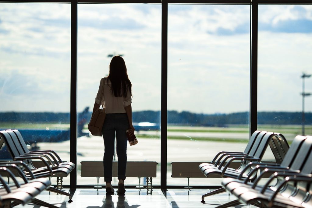 Silhouette of woman in airport lounge waiting for flight aircraft